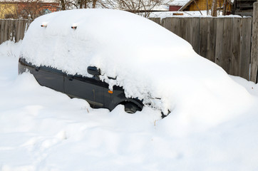 Car covered with snow in the winter snowfall