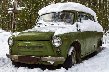 Retro green car stands in the winter forest