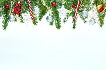 new year holiday white background with christmas tree branches, various decorations and glowing light garlands