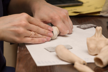 Girl hands polishing parts for making dolls from polymeric material.
