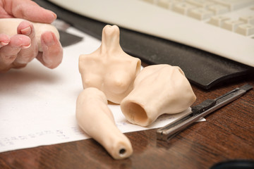Girl hands polishing parts for making dolls from polymeric material.