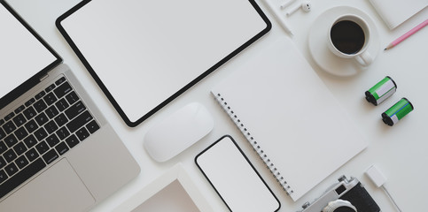 Top view of photographer workplace with blank screen tablet, laptop computer, vintage camera and office supplies