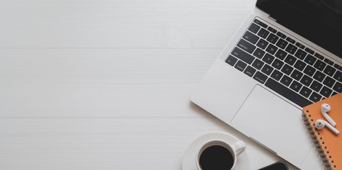 Top view of minimal workplace with laptop computer, coffee cup and office supplies