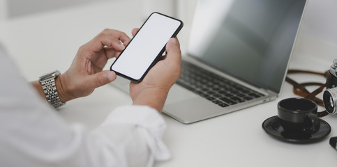 Cropped shot of businessman looking for information on blank screen smartphone