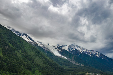 Obraz na płótnie Canvas Alpine mountains and Chamonix valley under cloudy sky 