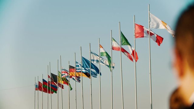 Flags of the world countries blowing in the wind on the background of early sunset in clear beautiful sky
