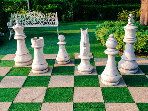 White chair in the middle of a wooden garden, with walkway a checkered pattern.