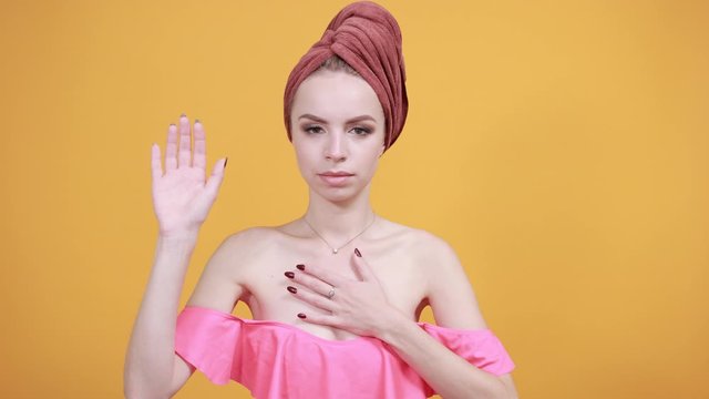 young girl with towel on her head over isolated orange background shows emotions
