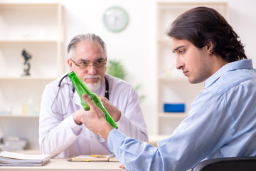 Obraz premium Young male alcoholic visiting old doctor