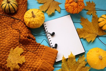 Naklejka na ściany i meble Autumn mockup. Fall Flat Lay.Blank notebook, decorative pumpkins set, autumn oak leaves,brown sweater, black headphones on a bright blue background.