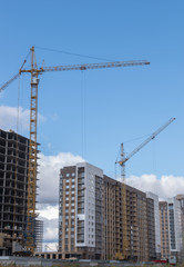 Fototapeta na wymiar High rise building with cranes under construction. big building construction site against blue sky with white cloud. Industrial background