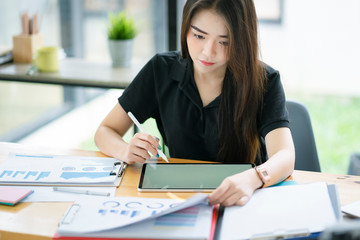 Young Asian businesswoman working on computor and graphics tablet in her working space