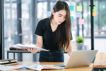 Young Asian graphic designer or businesswomanworking on computor and graphics tablet in her working space