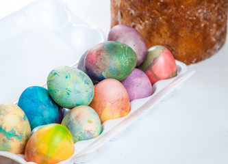 Easter cake and colorful eggs in tray on white background