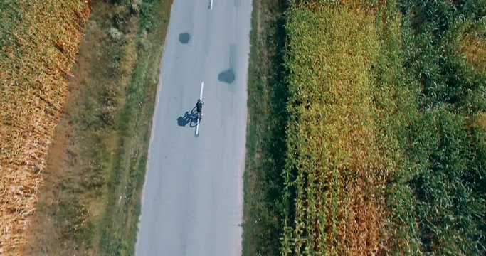 Aerial Triathlon Cyclist Riding On Time Trial Bike.Athlete Man Bicyclist Intensive Training Workout Before Hard Ironman Triathlon Race.Aerial Cyclist Triathlete Ride On Rural Road.Cycling From Drone.