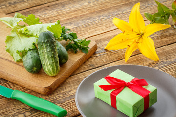 Just picked cucumbers and leaves of salad lying on cutting board with knife and plate.