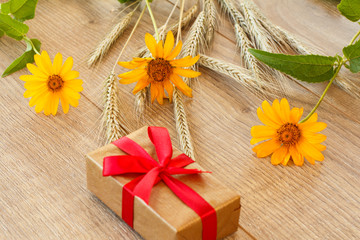 Obraz na płótnie Canvas Gift box, dry spikelets of wheat and flowers on wooden table.