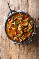 Homemade slowly cooked Lamb rogan josh close-up in a pan. Vertical top view