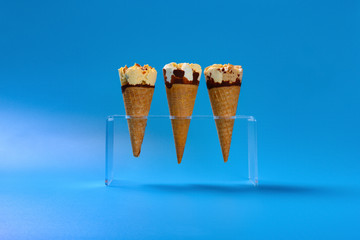 side view three different flavor ice cream cone on blue background