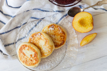 Cheesecakes with peach and jam on a wooden background
