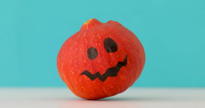 Little orange pumpkin dancing on blue background. Halloween holiday creative background with jack pumpkin
