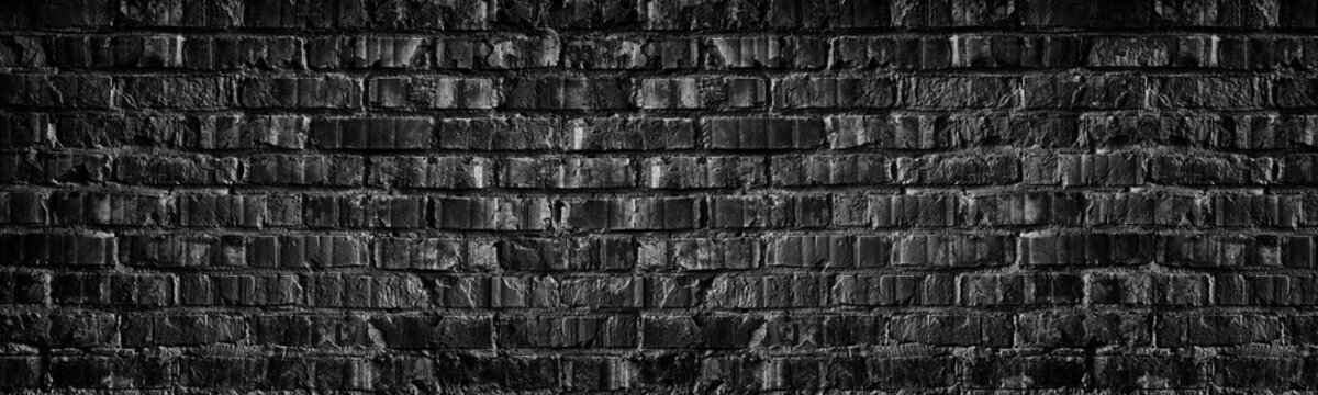 Wide black brick wall texture. Old rough dark grey brickwork masonry widescreen backdrop. Gloomy grunge panoramic background