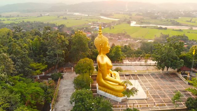 Point of interest Thailand Wat Jom Thong Golden buddha statue aerial footage view during sunset.