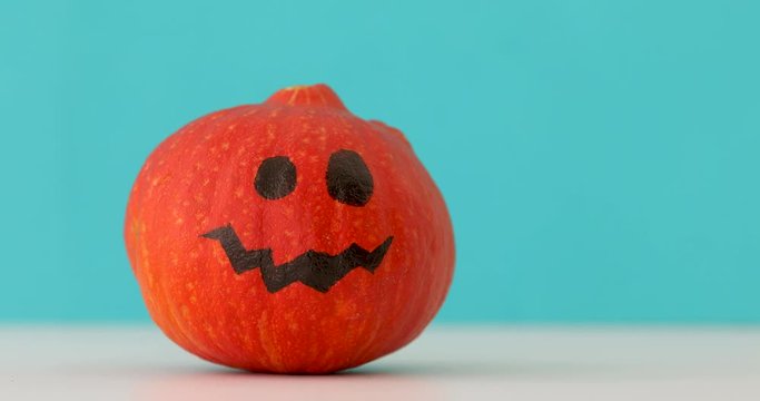 Little orange pumpkin dancing on blue background. Halloween holiday hand moves jack pumpkin