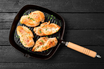 Fresh chicken breast seared in a cast iron skillet with baked potato and arugula salad.