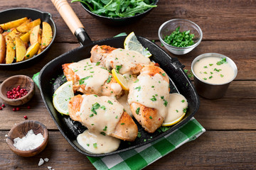 Fresh chicken breast seared in a cast iron skillet with creamy pan sauce.