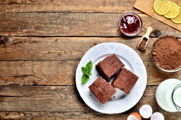 Traditional Czech gingerbread cakes, dried pieces of lemon, cacao powder, eggshells, jug of milk and raspberry jam on white plate. View from above.