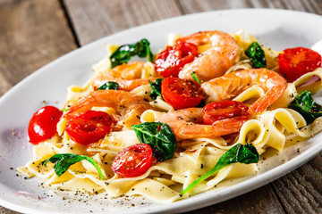 Shrimps with pasta tagliatelle with spinach and tomatoes