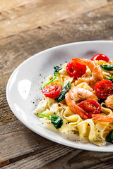 Shrimps with pasta tagliatelle with spinach and tomatoes