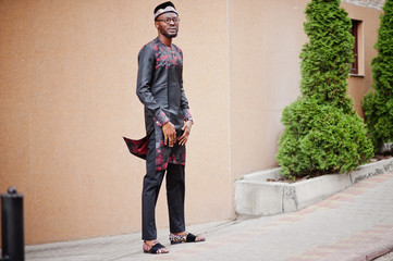 Handsome afro american man wearing traditional clothes, cap and eyeglasses in modern city.