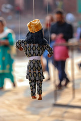 Puppets in traditional Nepali dresses hanging by a thread