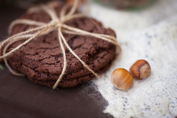 Hazelnuts in the peel and oatmeal cookies on brown table.  Baking is folded in a row on each other and tied with braid. Close up image