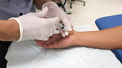 Doctor giving the anti-inflammatory drug injection to patient ‘s hand for treatment carpal tunnel...