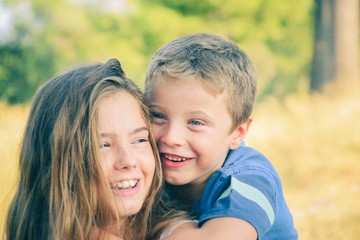 Brother on top of sister hugging her and smiling and having fun while doing piggyback