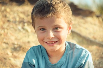 Smiling blonde kid with blue eyes wearing a blue t-shirt