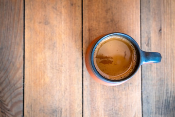 A cup of tea placed on a wooden table. Top view