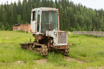 Old tractor on a field in the village in the summer