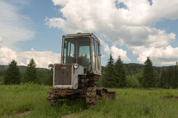 Old tractor on a field in the village in the summer