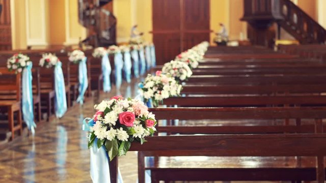 4K. interior view of empty church with wooden bench decorated with flower bouquet and blue ribbon blown by the wind with vintage filter, camera pan motion