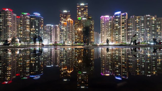 Timelapse of Busan Marina city in night with reflection in water, South Korea