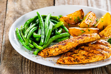 Grilled chicken fillets, baked potatoes and green beans