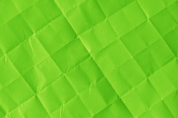 Folded and crumpled sheet of ufo green color paper texture background