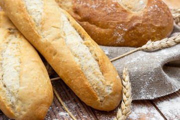Fresh bread with wheat ears on the table. Close up.