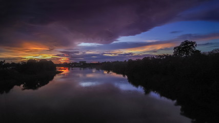 view low light evening above Mae Klong River around with green forest and cloudy sky background, sunset with raining in Ban Pong District, Ratchaburi, Thailand.
