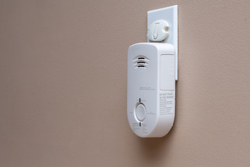 Carbon Monoxide (CO) monitor plugged into the wall of a residential house for safety.
