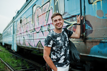 Fototapeta na wymiar Lifestyle portrait of handsome man with backpack posing on train station.